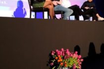 Charly Wai Feldman, Séan Binder und Sarah Mardini auf einer Bühne vor einer Kinoleinwand, vor der Bühne ein Eimer mit rosa Tulpen