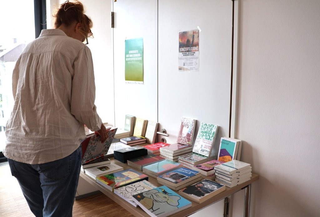 Eine Person blättert in einem Buch an einem Büchertisch, der vor einer Tür aufgebaut ist.