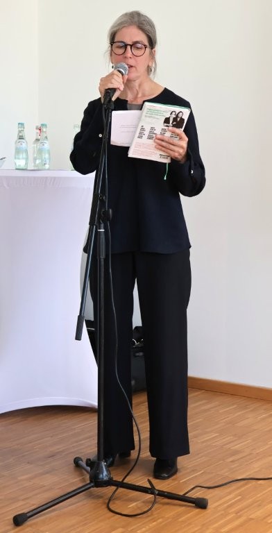 Eine Frau an einem Mikrofon stellt ein Buch vor.