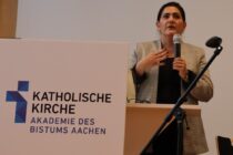 Eine Frau spricht an einem Pult der Akadamie des Bistums Aachen in ein Mikrofon.