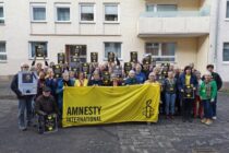 Gruppenfoto der Teilnehmer*innen der Amnesty Regionalkonferenz West in der Bonner Brüdergasse. Sie zeigen Solidaritätsbotschaften für die Ukraine auf Plakaten.