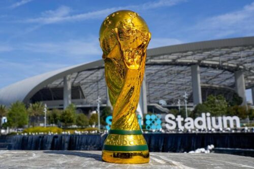 Fußball-WM-Pokal der Männer im Sonnenlich vor einem Stadion